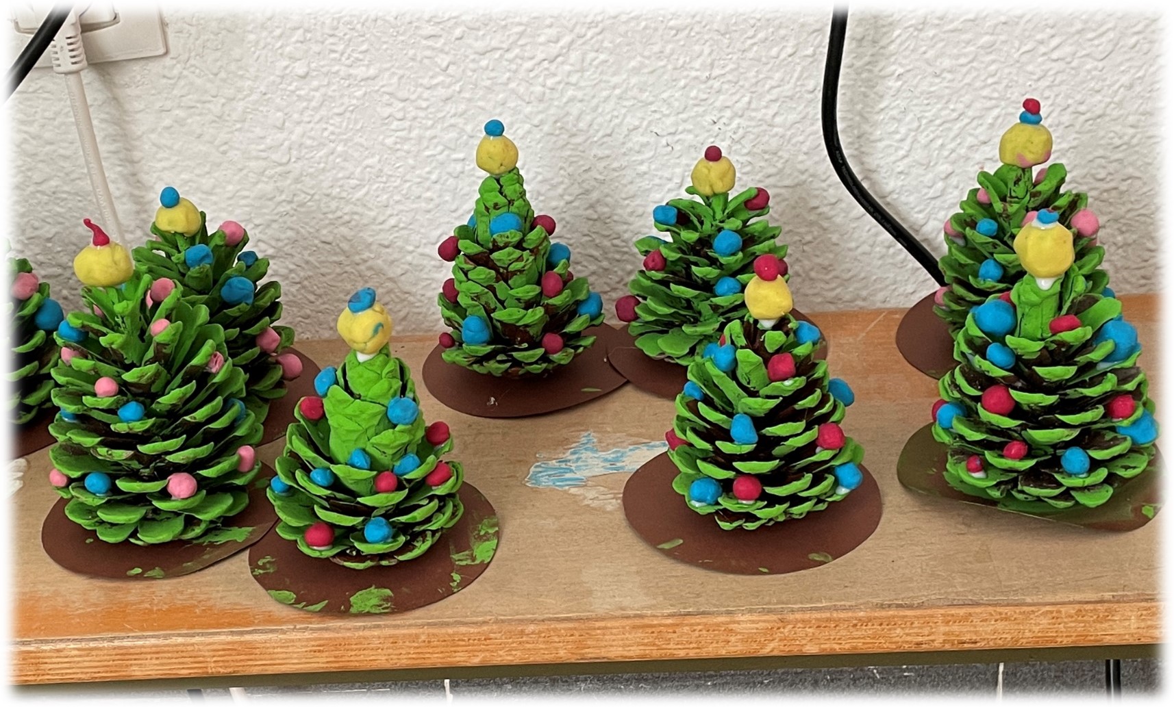 arboles de navidad hechos con piñas por niños de educación infantil